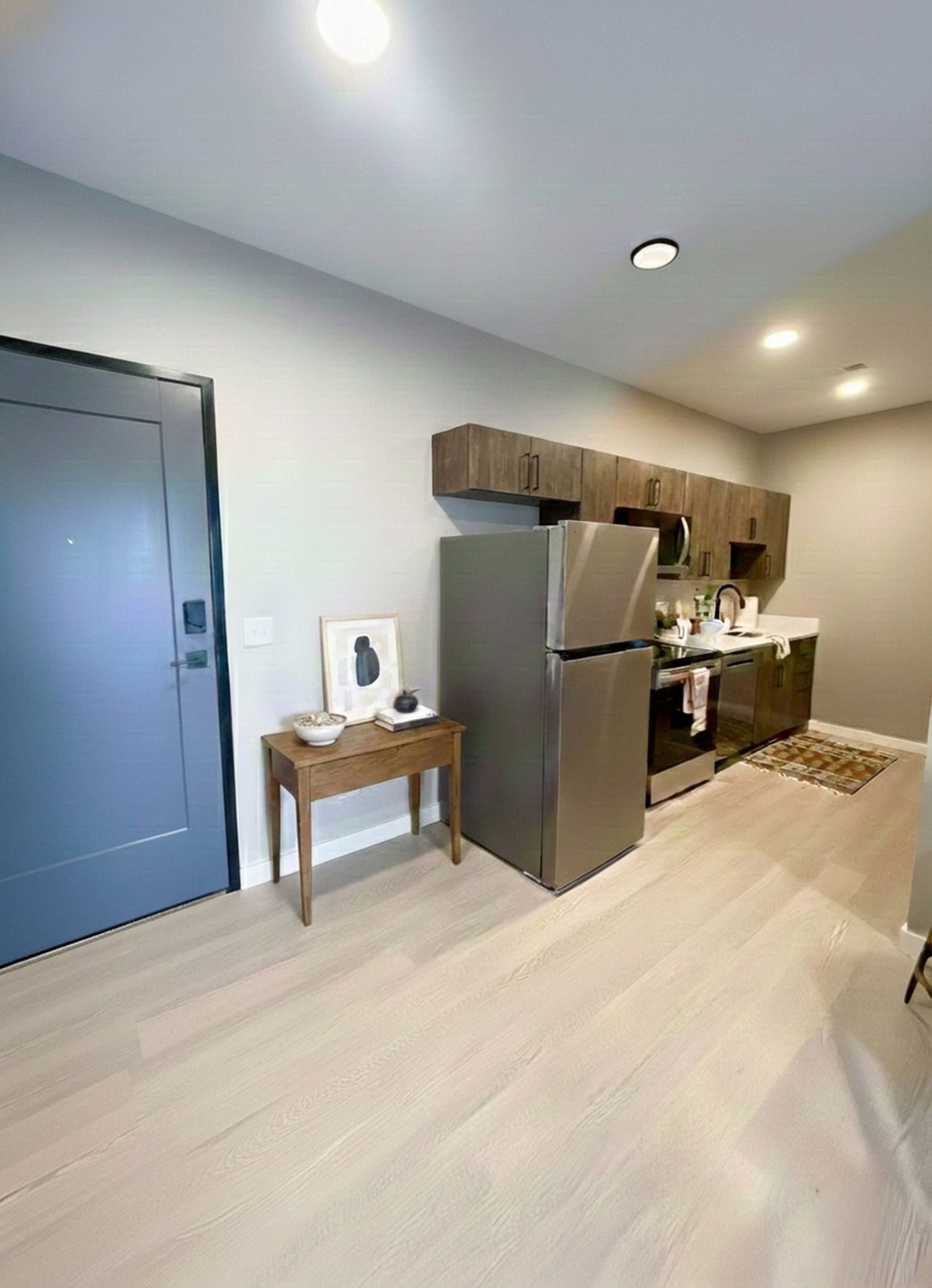 Small kitchen with stainless steel appliances, wood cabinets, and light wood flooring.