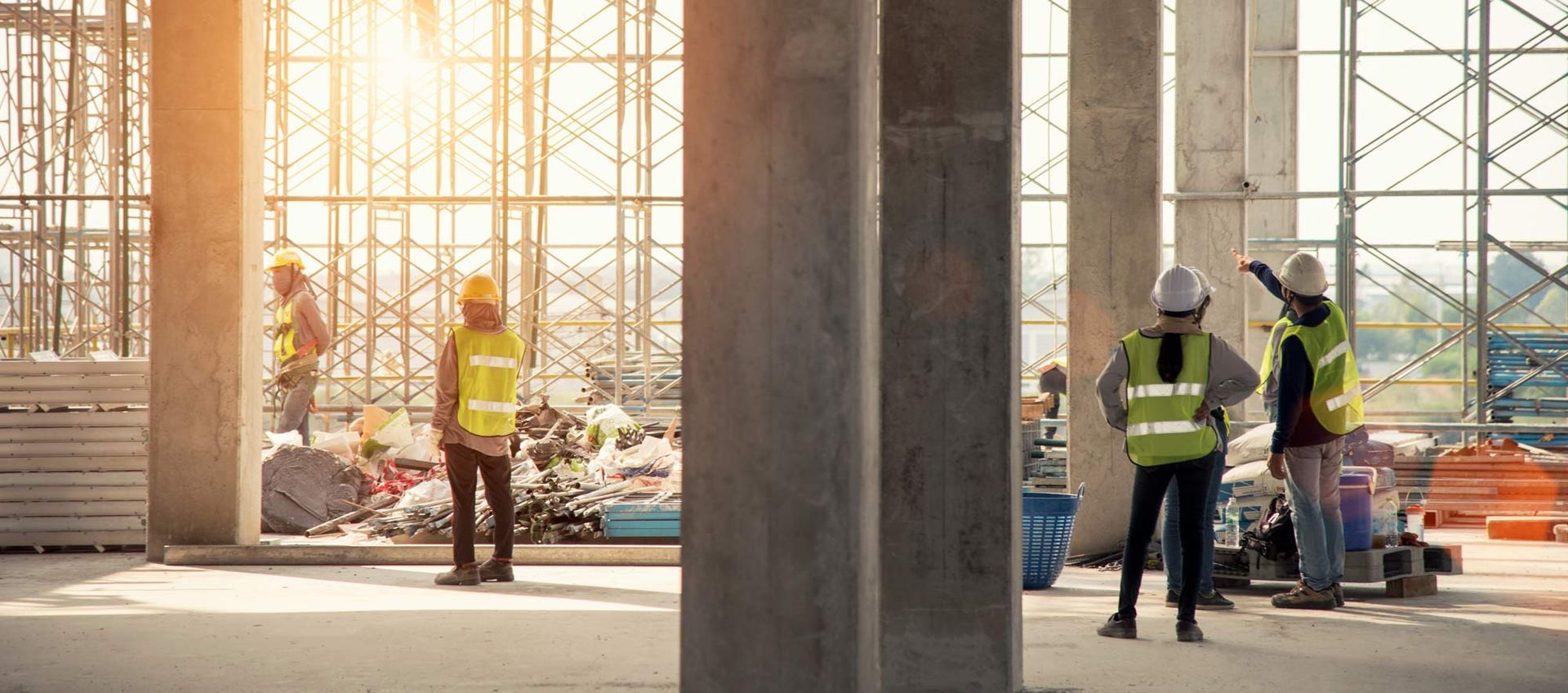 A group of construction workers are standing in a building under construction.