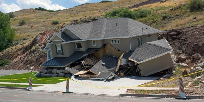House damaged by a landslide on a hillside. The house is collapsing and debris is scattered. How Geotechnical Engineering Can Mitigate Landslide Risks