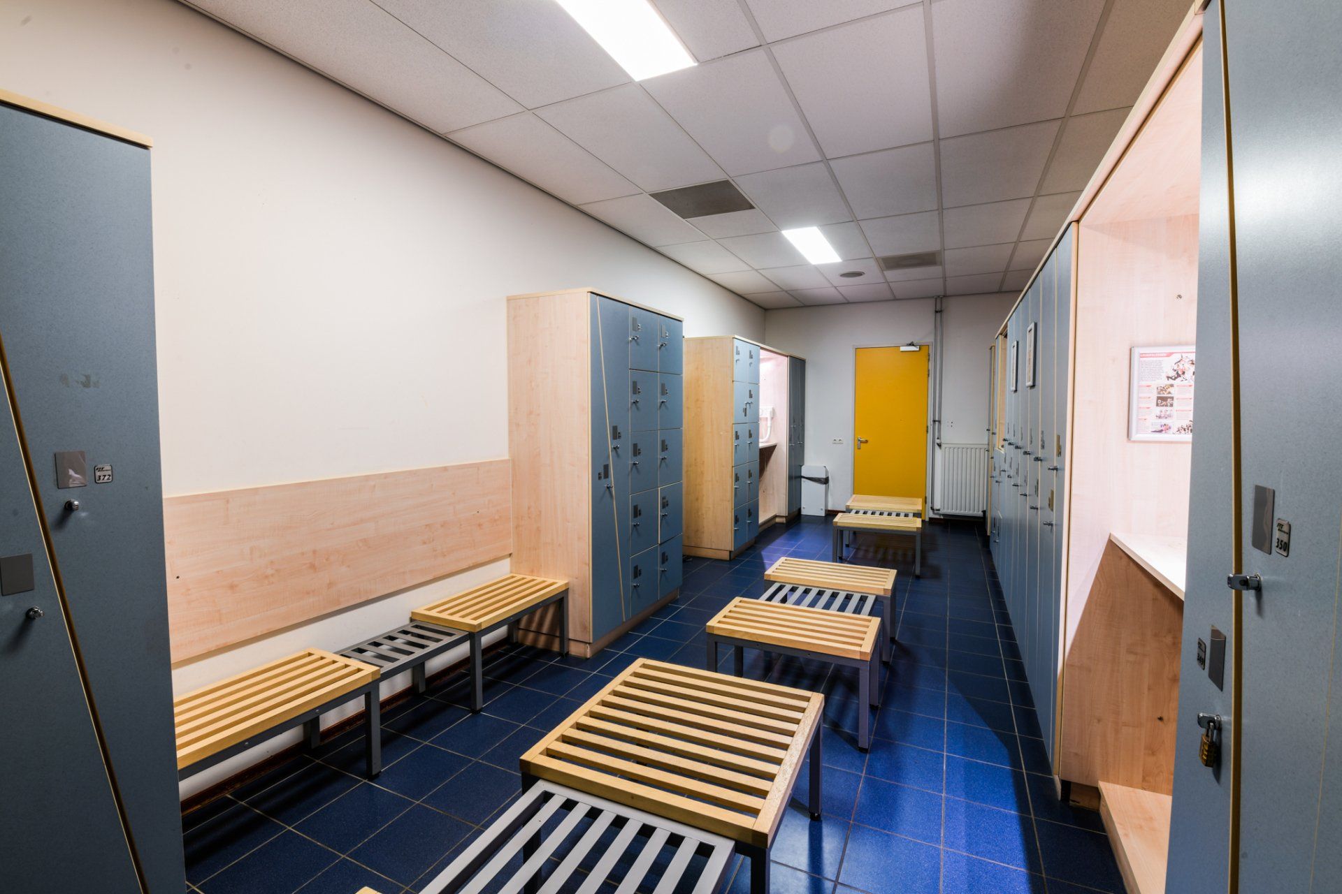 Een kleedkamer met veel kluisjes en bankjes.