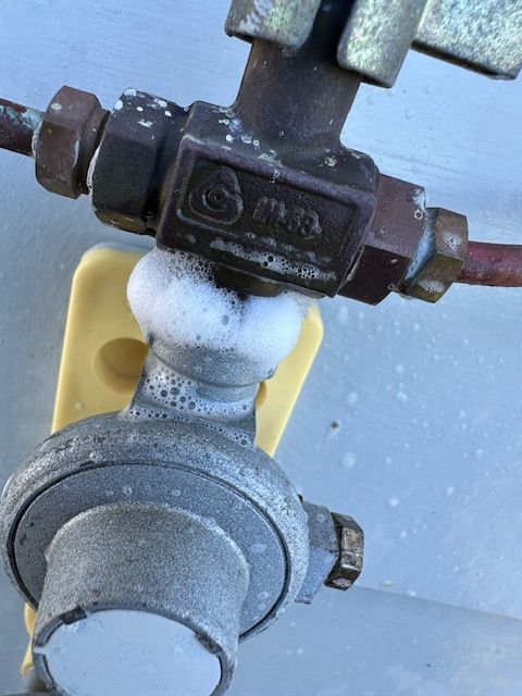 Soapy bubbles around a gas valve and regulator, indicating a leak — Gas Fitting Services in Bundaberg, QLD