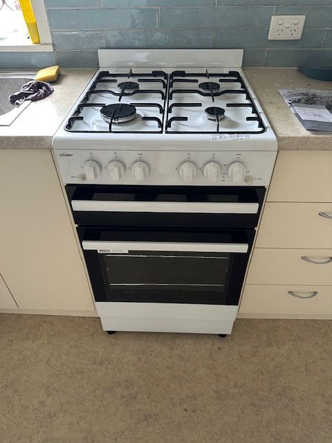 White gas range with four burners and two ovens in a kitchen — Gas Fitting Services in Bundaberg, QLD