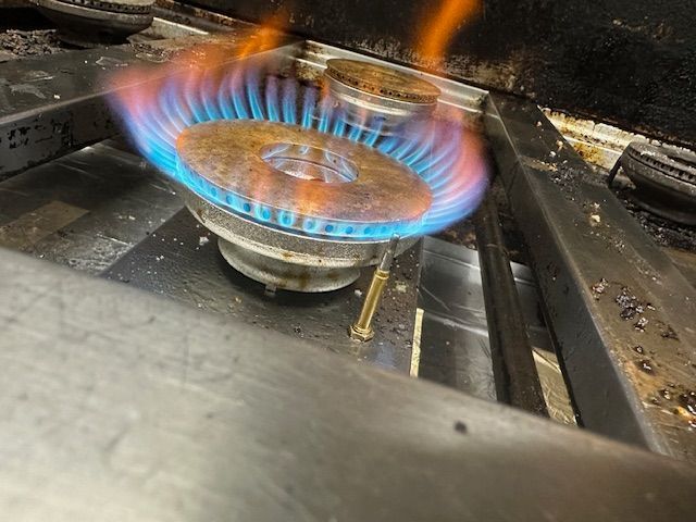Blue and orange gas flames burning from a dirty stove burner — Gas Fitting Services in Bundaberg, QLD
