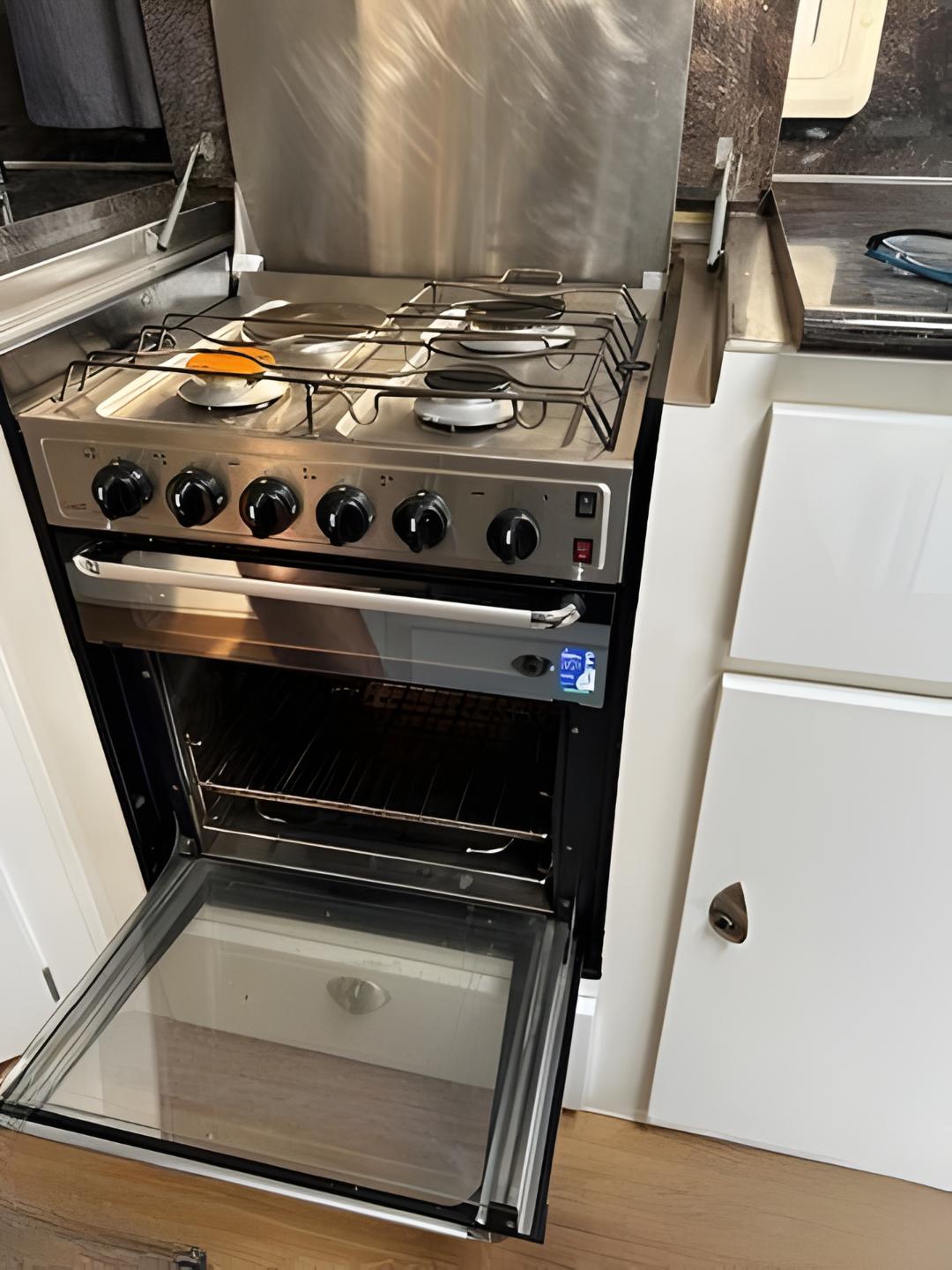 Stainless steel stove and oven unit in a campervan, oven door open — Gas Fitting Services in Bundaberg, QLD
