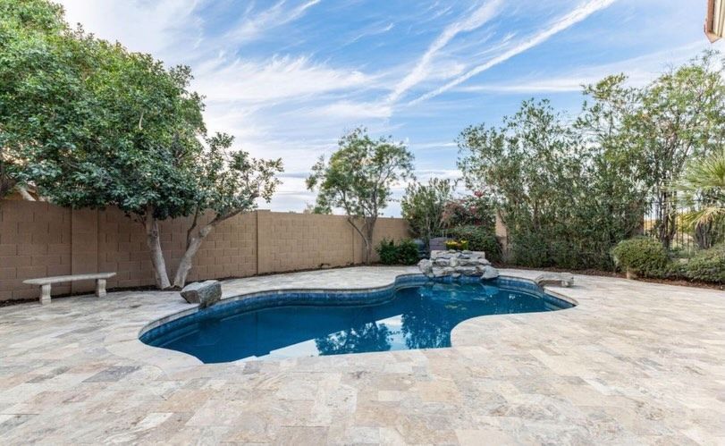Woman smiling, wearing a white turtleneck and necklace. The background shows a wooden staircase. 