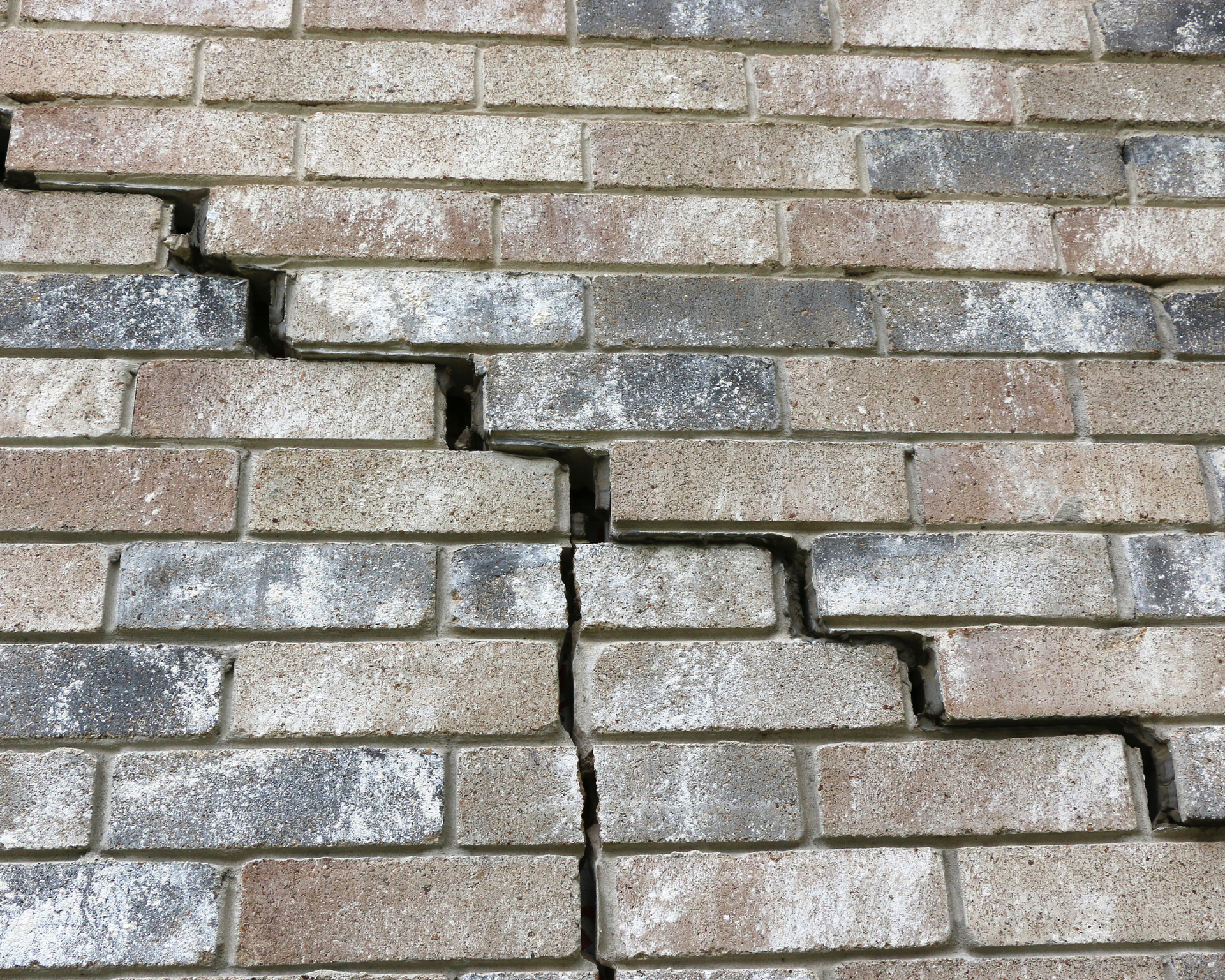 Brick wall with a large, jagged crack running vertically through it.