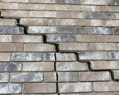 Cracked brick wall, with a prominent vertical crack running down the center.