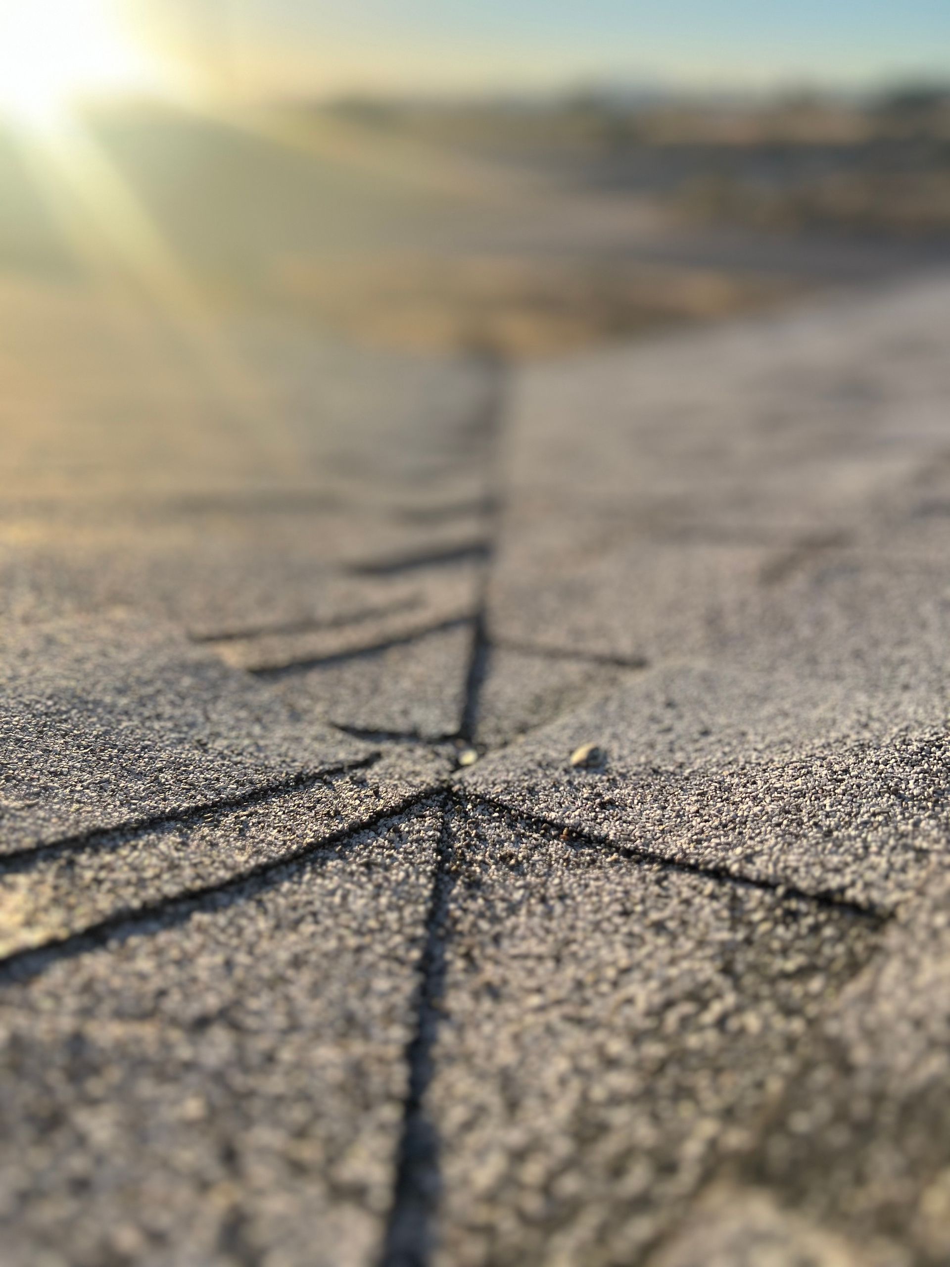 Close-up of a frost-covered surface with a linear, arrow-like pattern leading toward a blurred, sunny horizon.