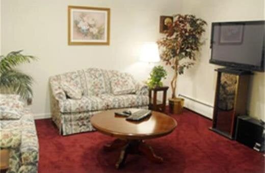 Living room with floral sofas, round coffee table, and large television.