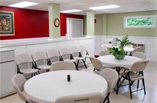 Interior of a community room with round tables, chairs, and a red and green wall.