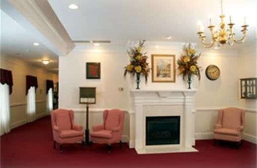 Lobby with fireplace, pink chairs, and hallway with red carpet. Elegant, well-lit space.