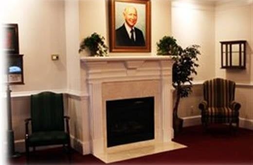 Formal living area with fireplace, portrait, and chairs.