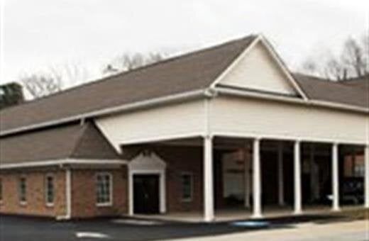 Building with brick facade, brown roof, and white columns.