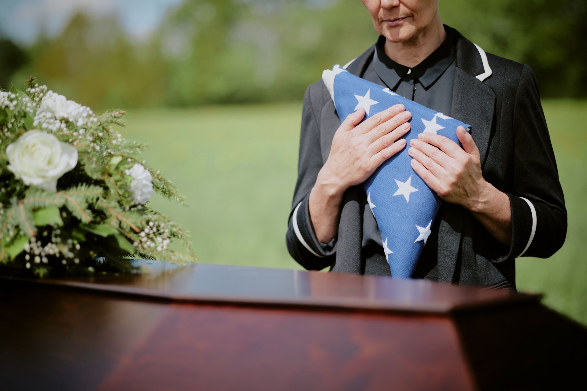 A man in a suit is sitting at a coffin at a funeral.