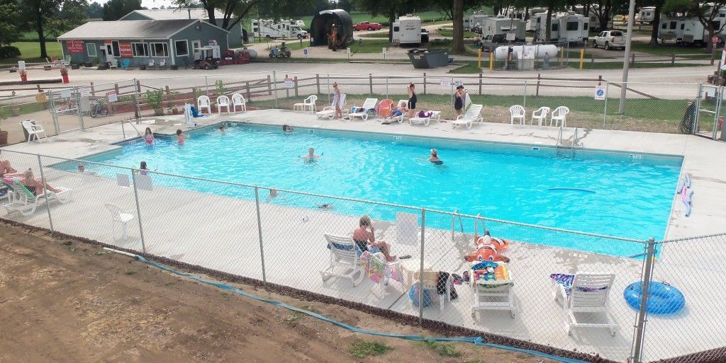 A large swimming pool is surrounded by chairs and a fence.