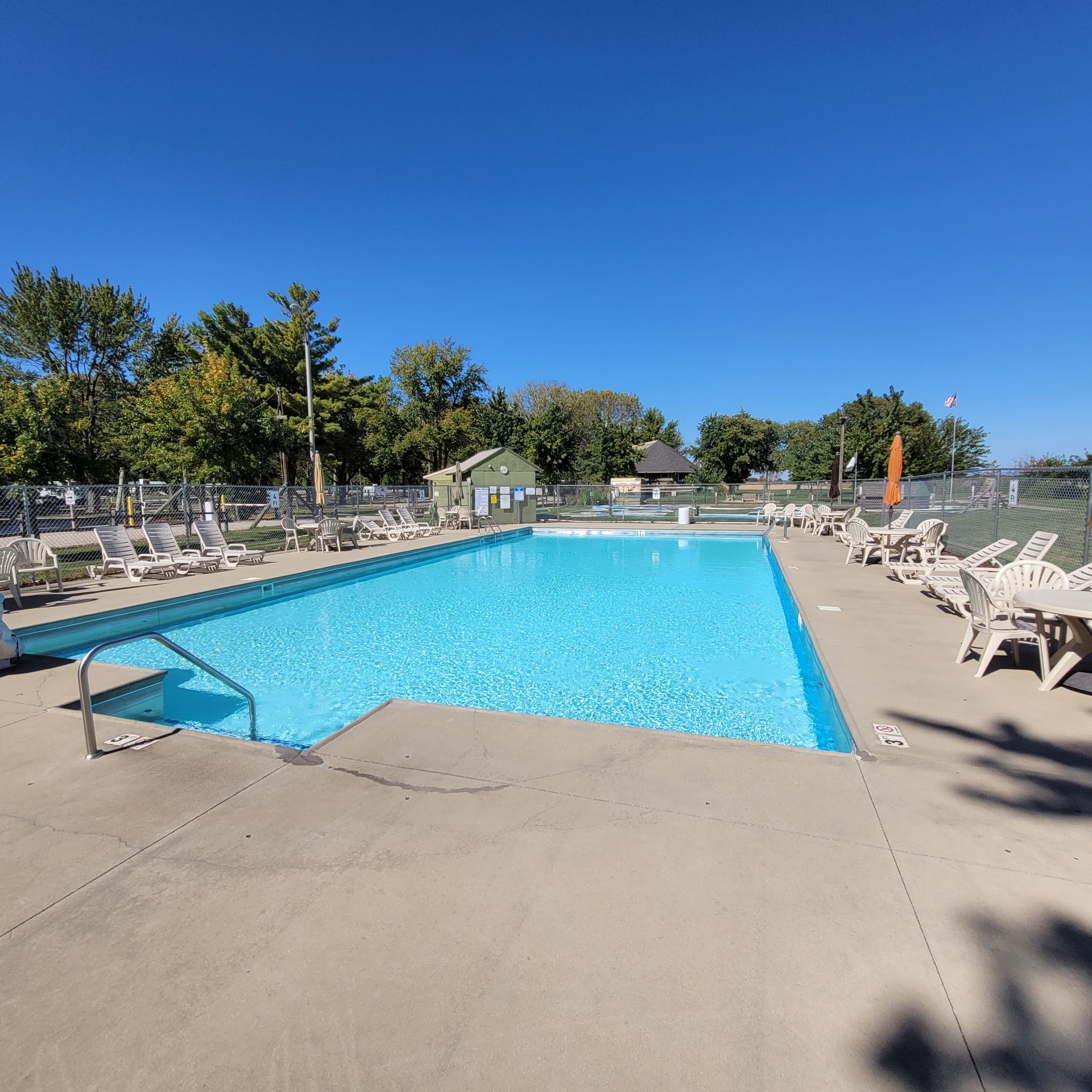 A large swimming pool surrounded by chairs on a sunny day