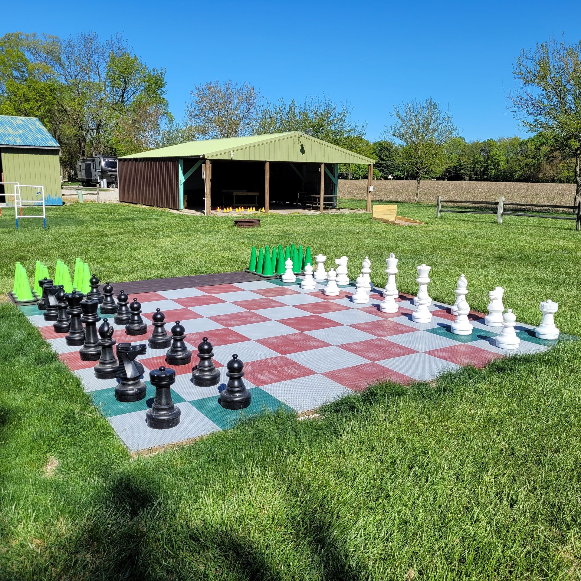 A large chess board is sitting on top of a lush green field.