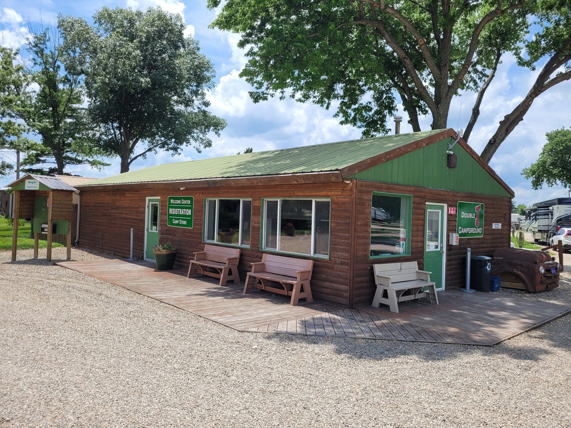A small wooden building with a green roof and benches in front of it.