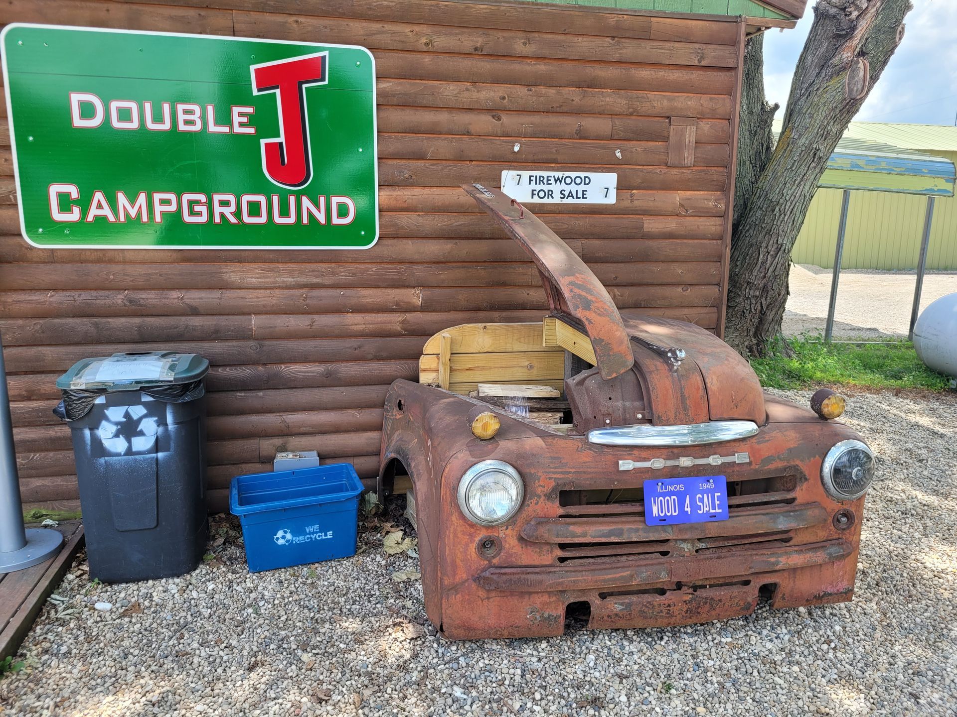 An old rusty truck is parked in front of a wooden building with a sign that says double j campground.