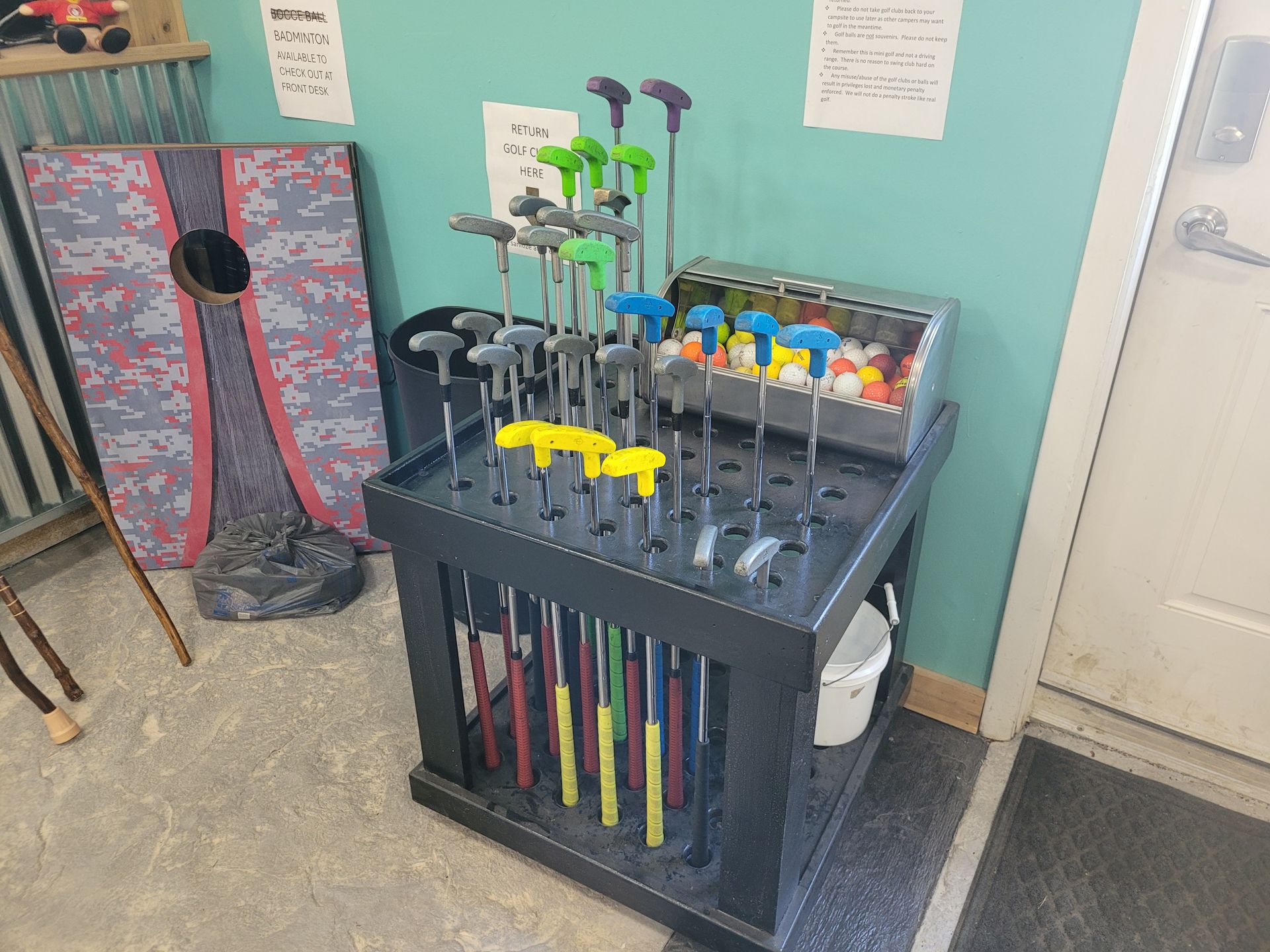 A bunch of golf clubs are sitting on a rack in a room.