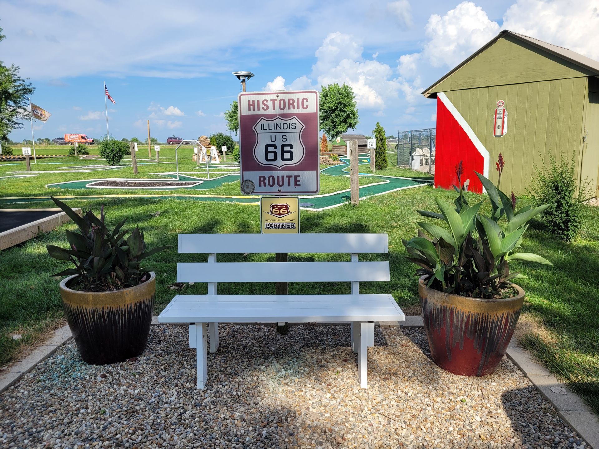 A white bench in front of a historic route 66 sign