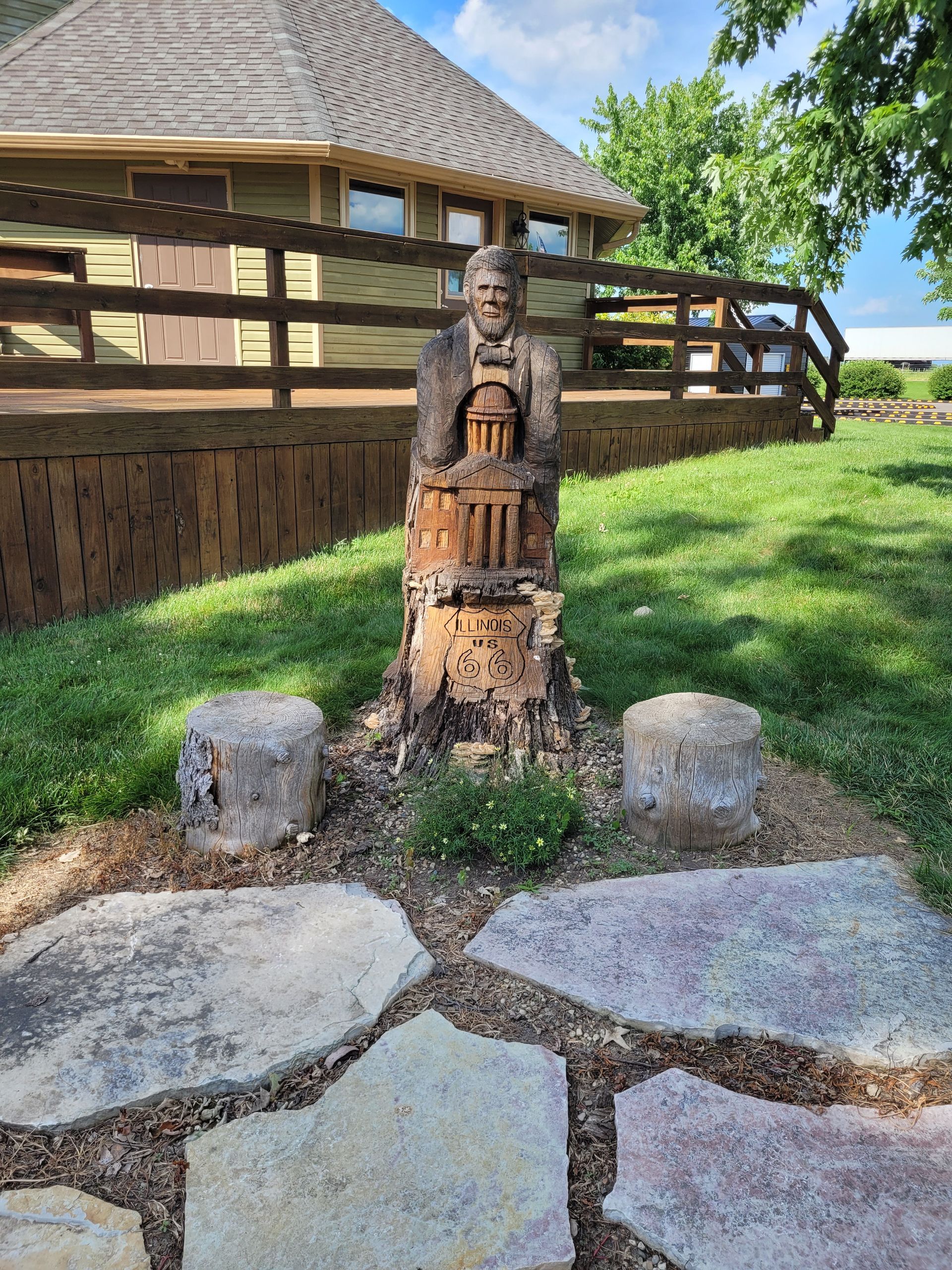 A statue of a man is carved into a tree stump in front of a house.