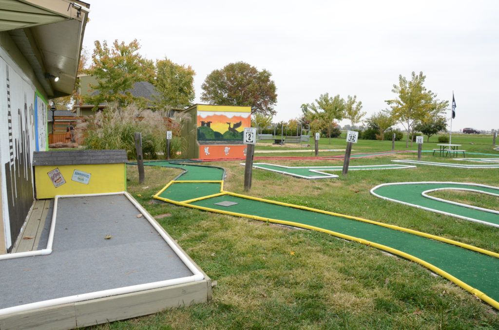 A mini golf course in a park with a house in the background