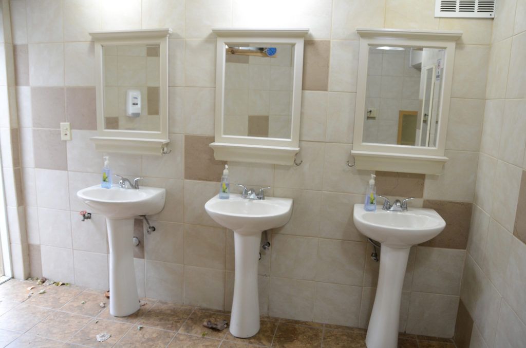 A bathroom with three sinks and three mirrors.