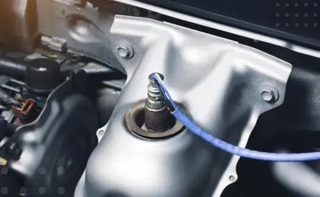 Oxygen sensor connected to the exhaust system of a car engine, used to monitor and control fuel effi