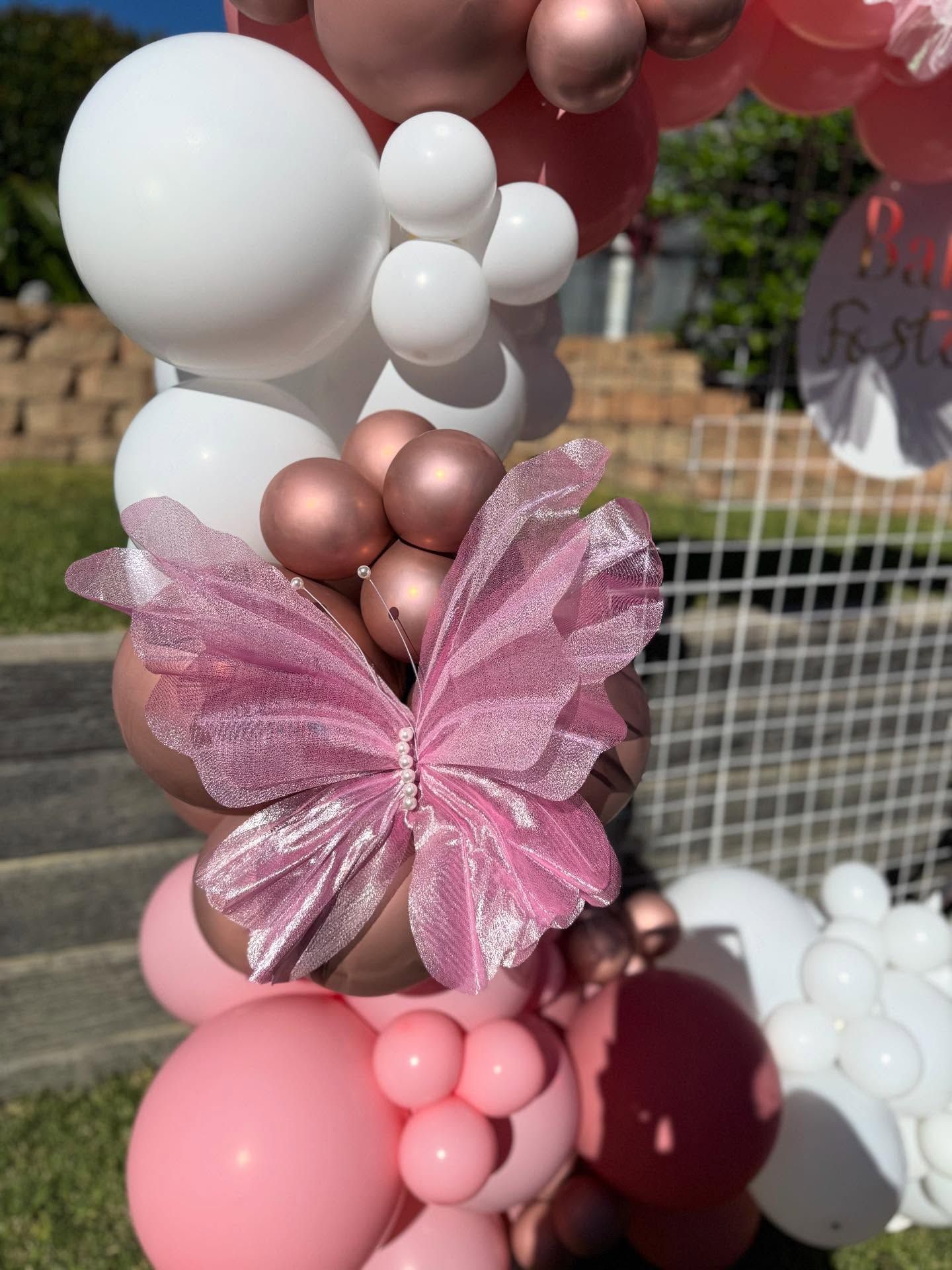 A balloon garland for 21st party with a neon sign that says let 's party
