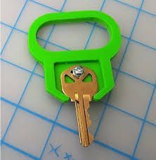 Green 3D-printed key holder with a brass key inserted, on a blue-grid background.