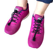 Person's feet wearing bright pink athletic shoes with black elastic laces and blue accents.