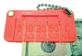 Red money identifier tool with slots labeled for different bills, held over a dollar.