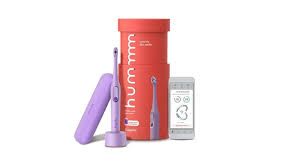 Purple Hum electric toothbrush set with a case, charging stand, and app on a phone.