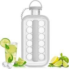White rectangular ice ball maker next to a glass of lime drink and fresh limes.