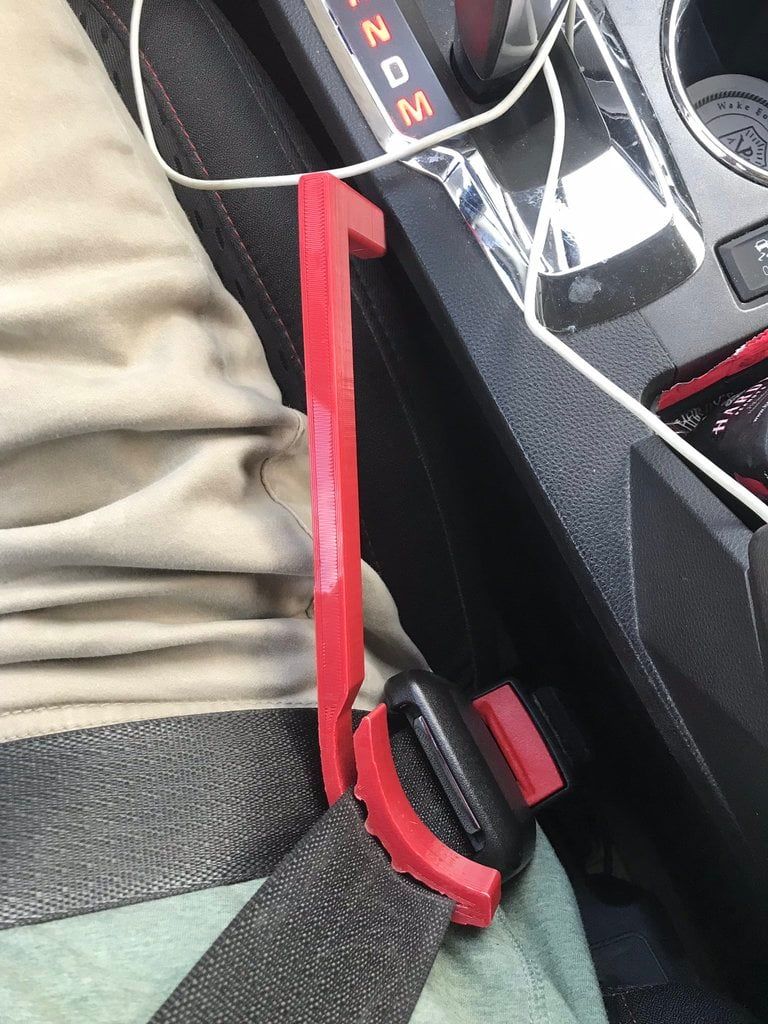 Red seat belt buckle release tool inserted into a car's seat belt buckle.