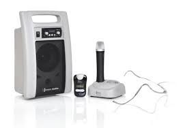 White portable speaker with microphone, transmitter, and charger.