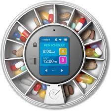 Circular pill dispenser with digital screen displaying a medication schedule. Compartments hold various colored pills.