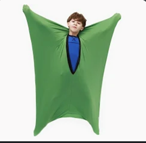 Boy in a green sensory body sock, arms outstretched.