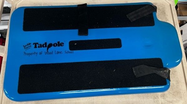 Blue Tadpole adaptive device with black straps and pads; text 