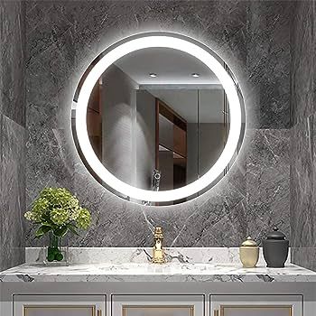 Round illuminated bathroom mirror above a marble vanity with gold fixtures and a floral arrangement.