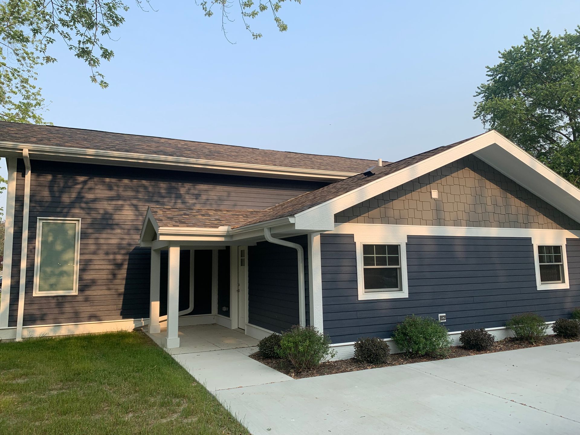 Blue house with white trim, concrete walkway, and green lawn.