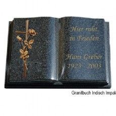Ein Grabstein in Form eines offenen Buches mit einem Kreuz und Blumen darauf.