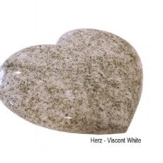 Ein herzförmiger Stein liegt auf einer weißen Oberfläche.