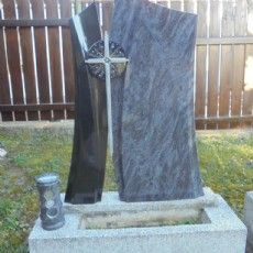 Ein Grabstein mit einem Kreuz darauf und einer Vase daneben.