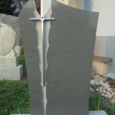 Ein Grabstein mit einem Kreuz darauf auf einem Friedhof.