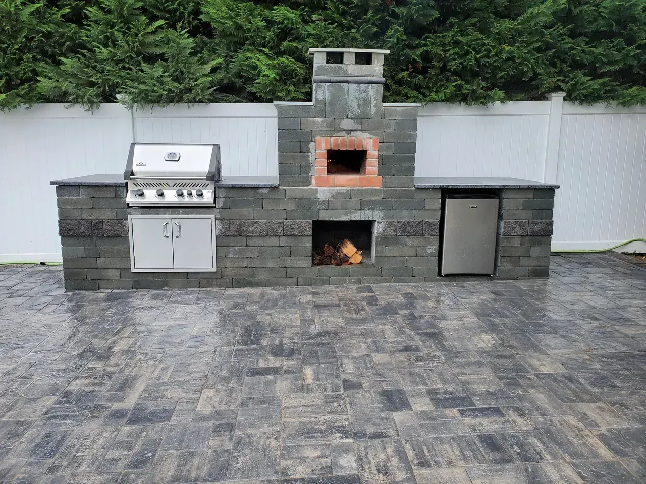 There is a grill and a pizza oven in the backyard.