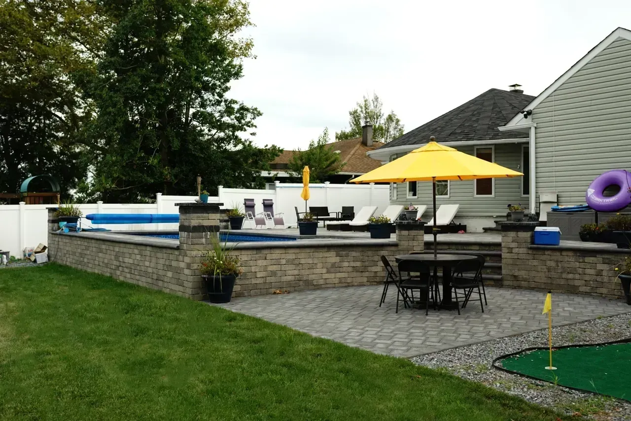 A backyard with a pool table chairs and umbrellas