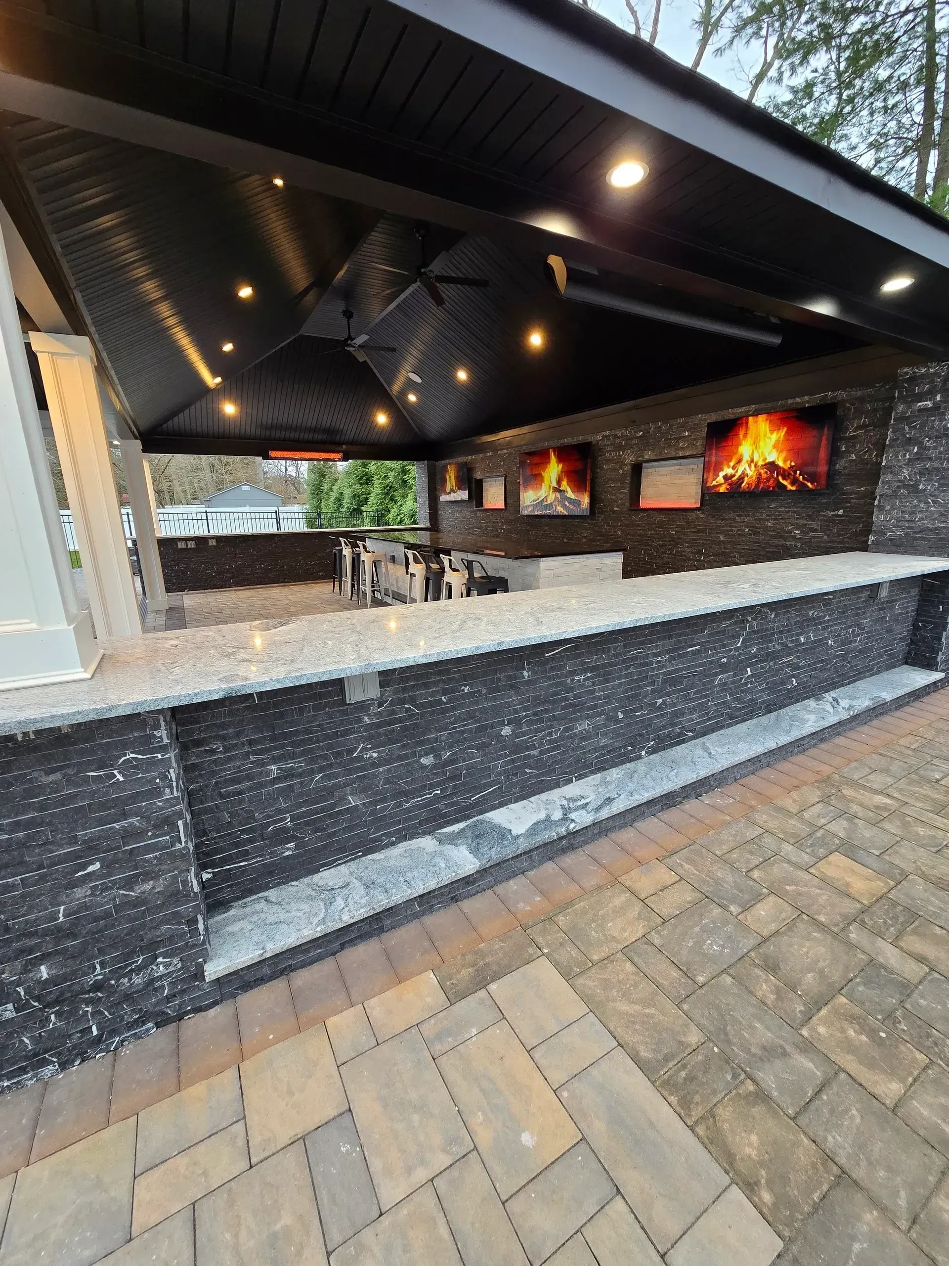 A large outdoor kitchen with a fireplace and a ceiling fan.