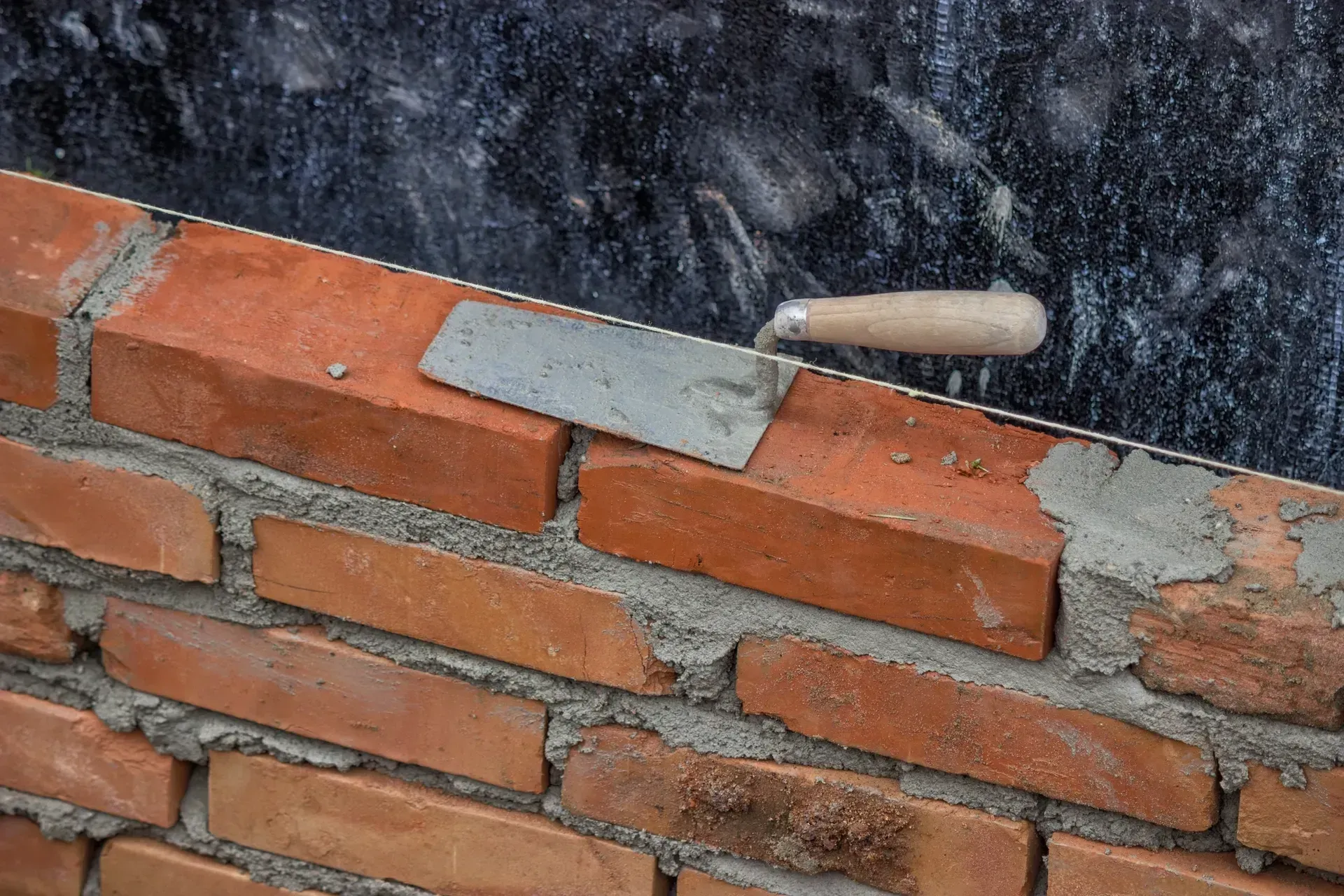 A trowel is laying on top of a brick wall.